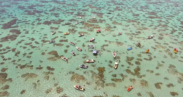 Aerial view of boats and people swimming in turquoise sea of Rio do Fogo, Brazil