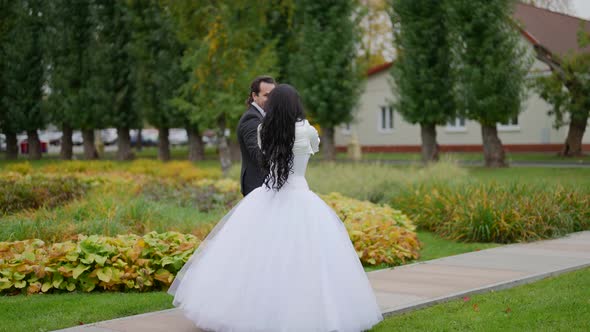 the Bride and Groom are Spinning on the Path in the Park Near the House