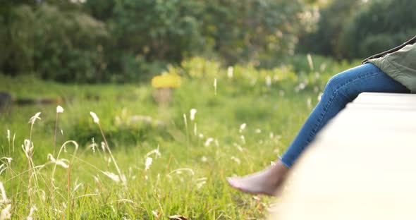 Woman sitting at the wooden walkway in countryside