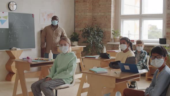 Kids and Teacher in Face Masks Posing for Camera in School Classroom