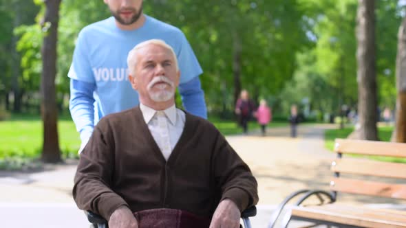 Male Volunteer Taking Care of Aged Disabled Patient Spending Time in Park