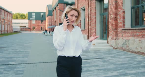 Successful Business Woman in White Shirt Speaking on Mobile Phone in Downtown