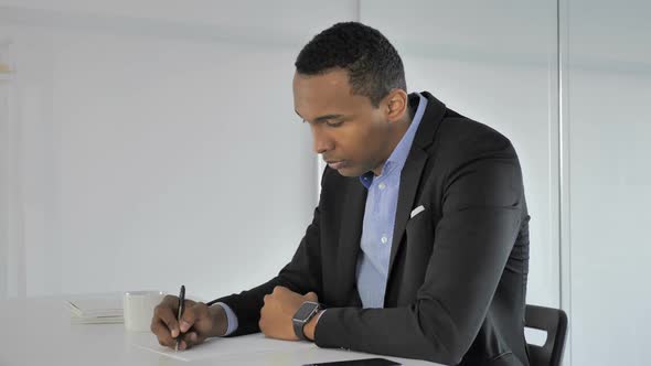 Casual AfroAmerican Businessman Writing at Work Paperwork