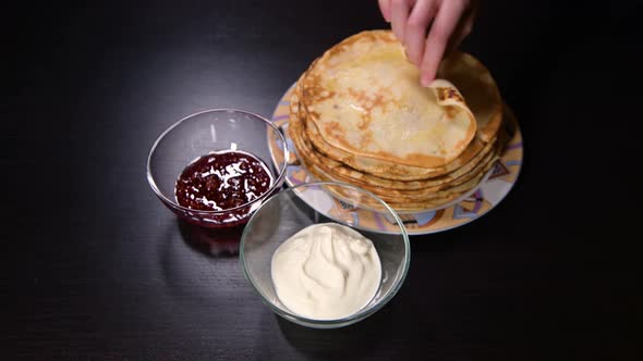 girl twists a pancake and dips it in sour cream