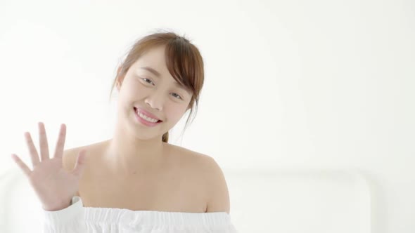 Beautiful portrait young asian woman sitting on bed with smile and happy at bedroom.