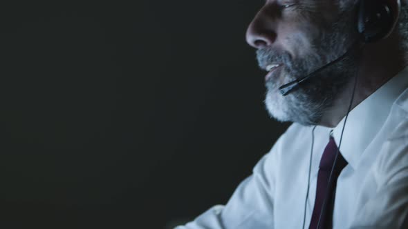 Mature Businessman in Headset Using Laptop