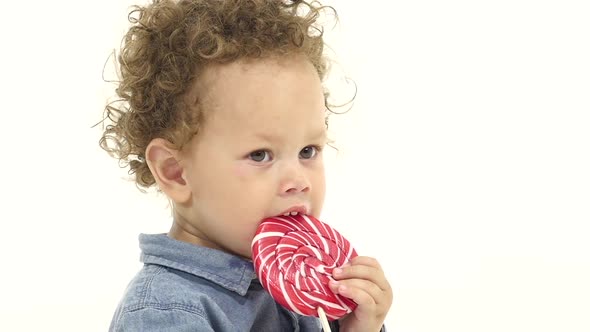 African American Boy Licks a Candy. White Background. Slow Motion. Close Up