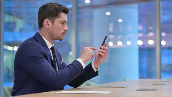 Busy Businessman Using Smartphone in Office