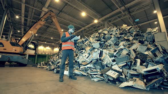 Landfill Worker Is Observing a Pile of Broken Office Machines