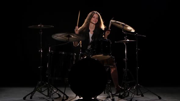 Drummer Girl Starts Playing Energetic Music, She Smiles. Black Background