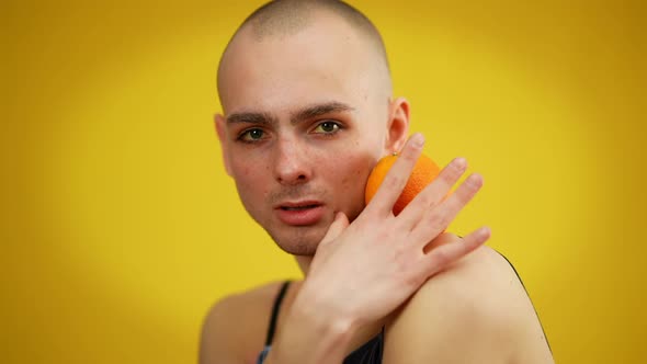 Portrait of Gay Man Posing with Orange at Yellow Background