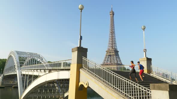 A couple running across a bridge with the Eiffel Tower.