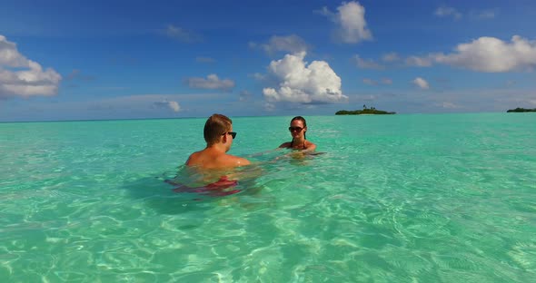 Beautiful lady and man on honeymoon vacation have fun on beach on sunny white sandy 4K background