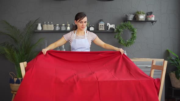 Young Woman Spreading Tablecloth on a Table