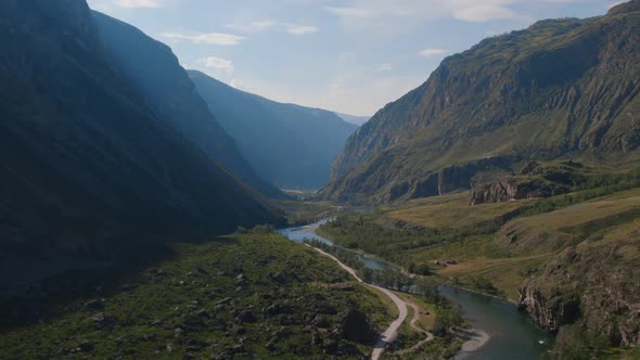 River Chulyshman between green field and mountains with blue clear sky in Altai