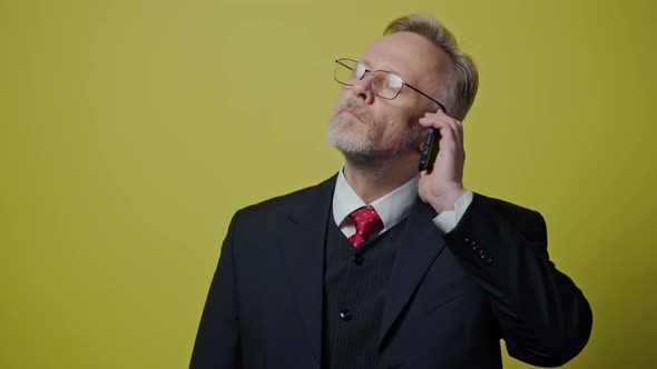 Serious elderly man talking the mobile phone. Senior businessman in black suit