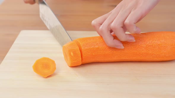 Woman hands cutting carrot on board