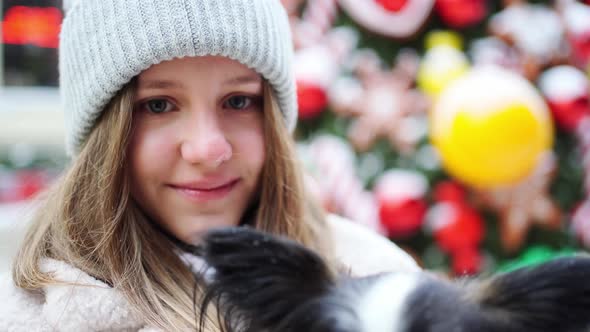 Beautiful Girl with Dog Papillon in Her Arms on Winter Christmas Streets