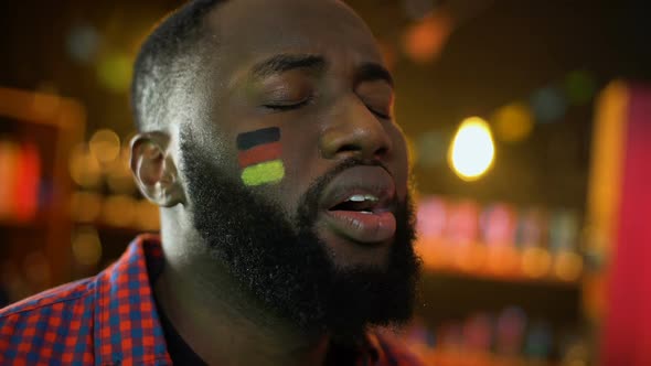 Disappointed German Football Fan With Flag on Cheek Making Facepalm, Team Losing