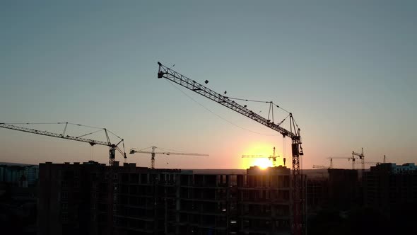 Aerial Drone View of Silhouette Construction Cranes in Sunset Light. Construction Site Building