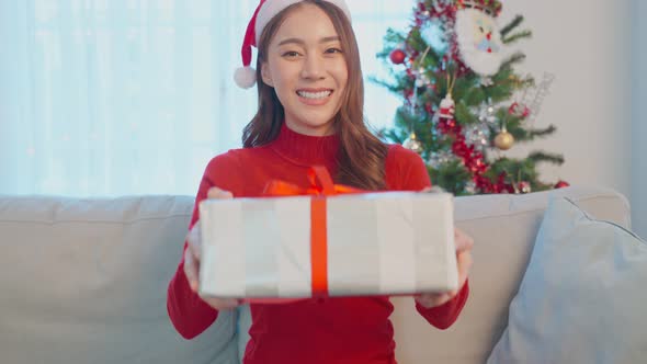 Portrait of Asian beautiful young woman smiling and holding Xmas present gift box with happiness.