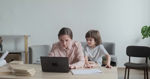 Freelance Mom is Focused on Typing and Working Remotely at Home on Laptop