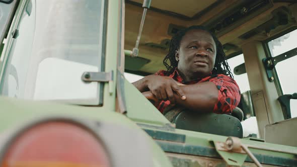 Young African Farmer Sitting in the Tractor Cabine and Showing Thumbs Up As Approval