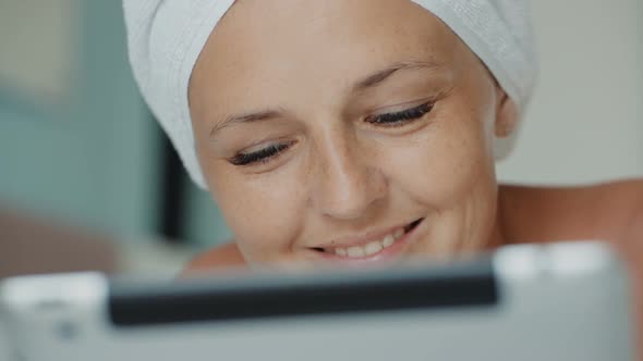 Woman in Bath Towel Browsing Social Media Posts While Lying on Couch