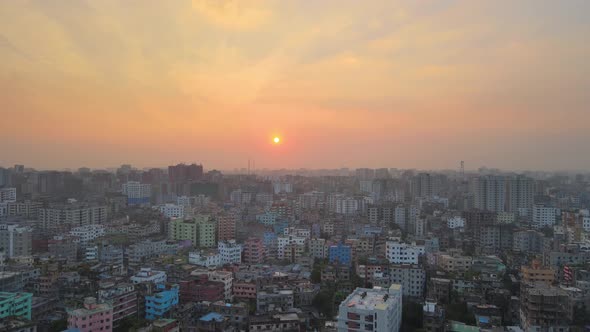 Aerial Over Khilgaon Thana Cityscape With Hazy Orange Sunset Skies. Pedestal Up