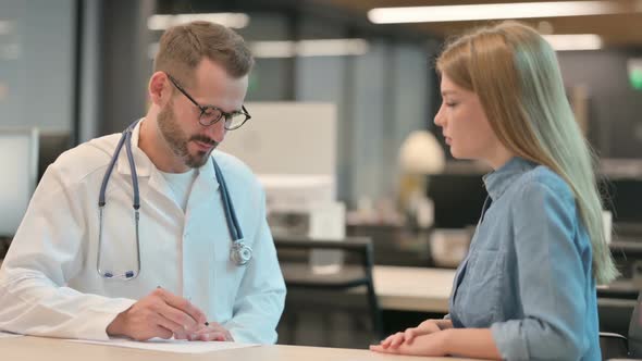 Middle Aged Male Doctor Doing Consultation with Female Patient