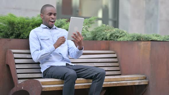 African Man Celebrating Success on Tablet Outdoor
