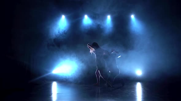 Modern Romantic Choreography Against Black Background with Spotlights in Smoke at Studio