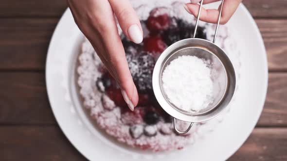 Female Hands with Metal Sieve Sprinkling a Cake with Powdered Sugar