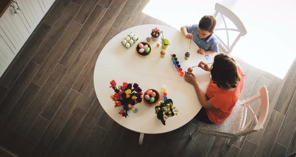 Young Mother and Her Son Having Fun While Painting Eggs for Easter