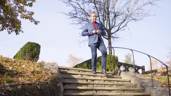 A Middleaged Handsome Caucasian Man Walks Down a Stone Staircase in a Rural Area in Fall