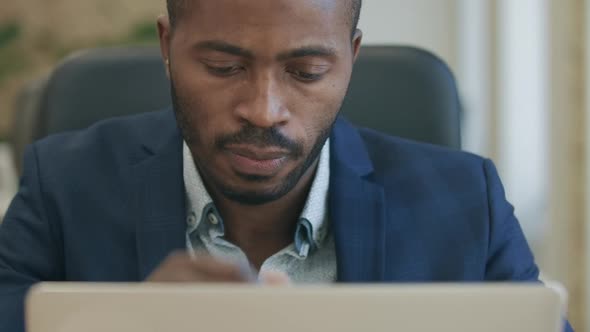 Close-up of Focused Bearded African American Man Typing on Laptop Keyboard and Thinking. Portrait of