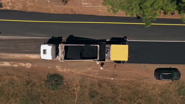 Asphalt paving machine escorted by an Asphalt truck at work, Top down aerial view.