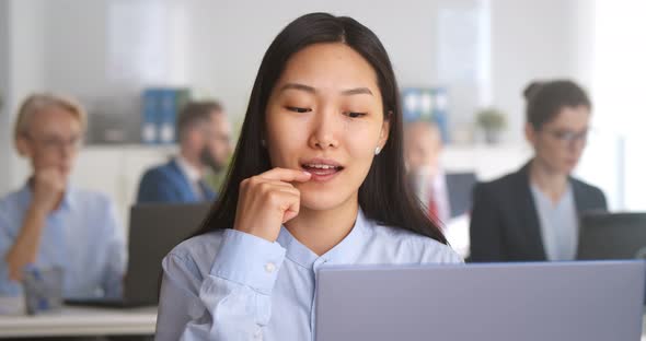 Asian Businesswoman Working on Laptop at Desk in Open Space Office