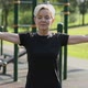 An Elderly Woman Does a Warmup in the Park on the Playground - VideoHive Item for Sale