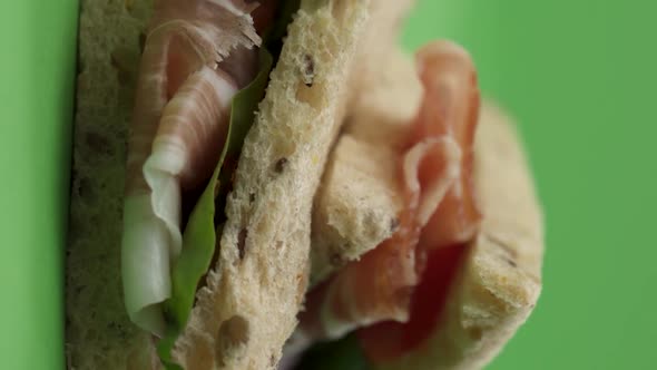 Vertical video, Close-up: delicious sandwich with salami, tomato and prosciutto