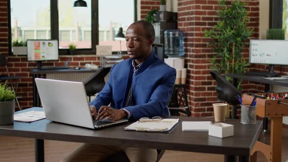 Company Worker Using Documents and Research on Laptop to Take Notes