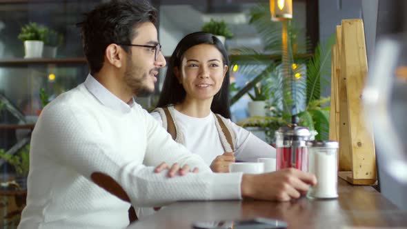 Young Couple Smiling and Chatting in Cafe