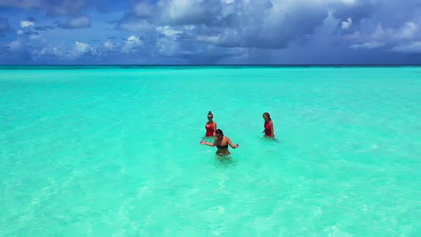 Sexy beauty models on photoshoot having fun on the beach on paradise white sand and blue background 