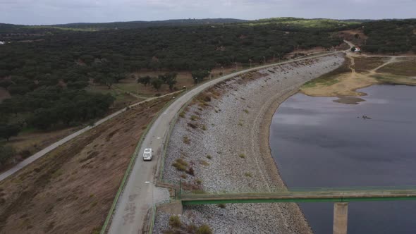 Camper van motorhome drone aerial view passing a dam road with the lake reservoir in Divor Dam in Al