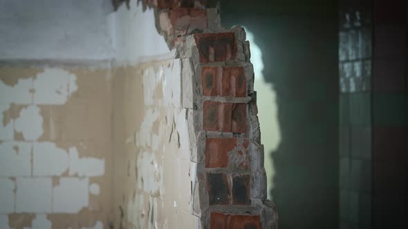 A Worker with a Sledgehammer Demolishes a Brick Wall