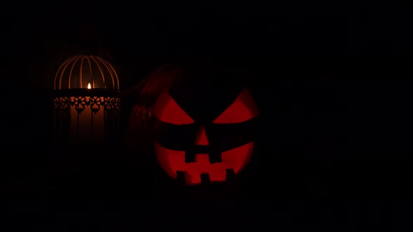 Scary laughing pumpkin and an old skull over the frightening gothic background.