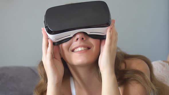 Young Blonde Woman Playing Game Using VR-helmet for Smart Phones.