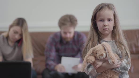 Portrait Little Sad Unhappy Girl with Toy in Hands Looking in Camera. Young Woman Typing 