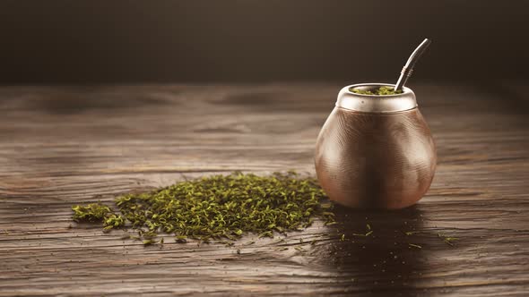 Yerba mate in gourd. Calabash with bombilla next to the pile of shredded leaves.