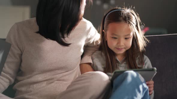 Smiling mother and daughter looking at the tablet